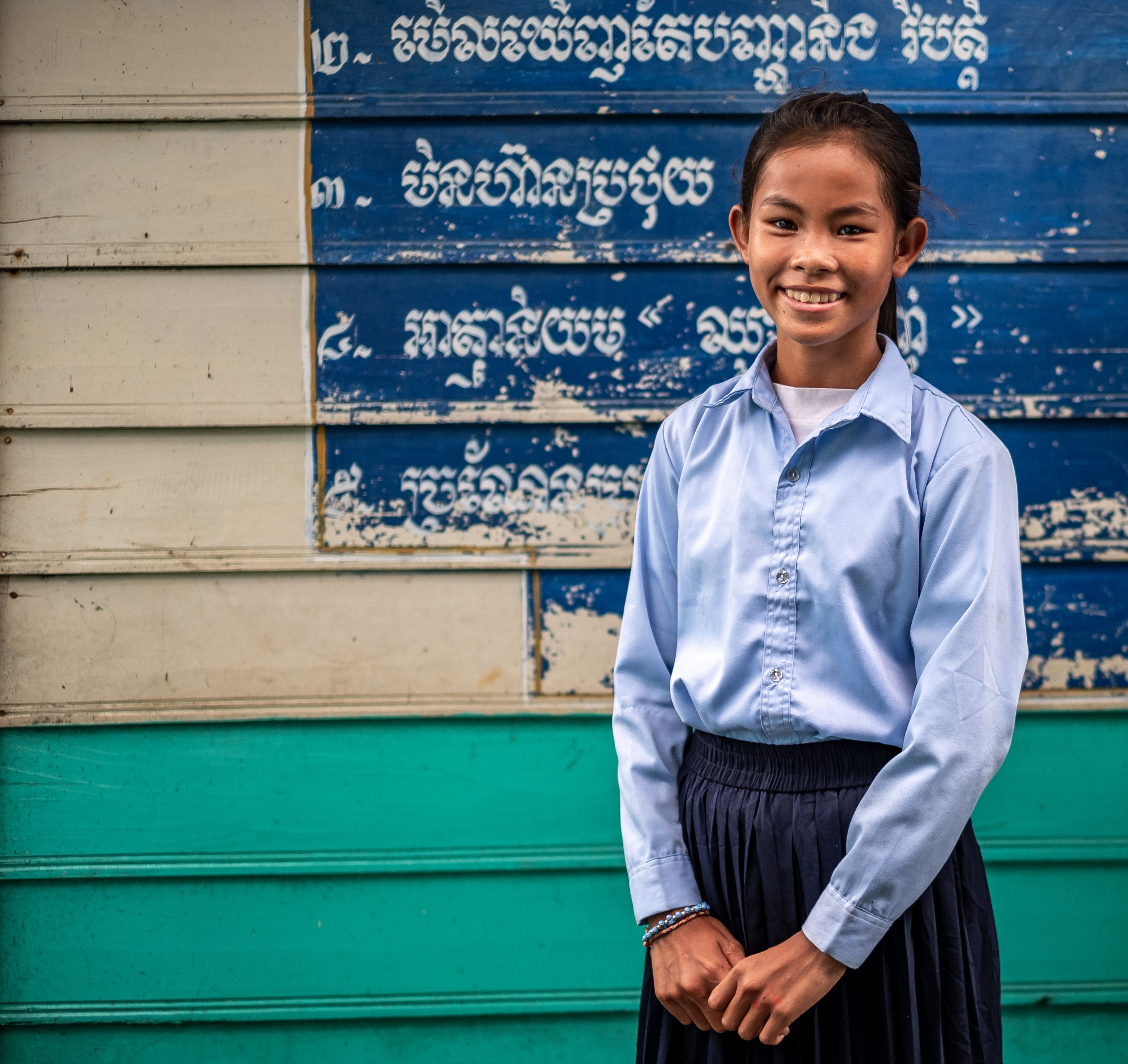 Photo of a child in front of a school in Cambodia.