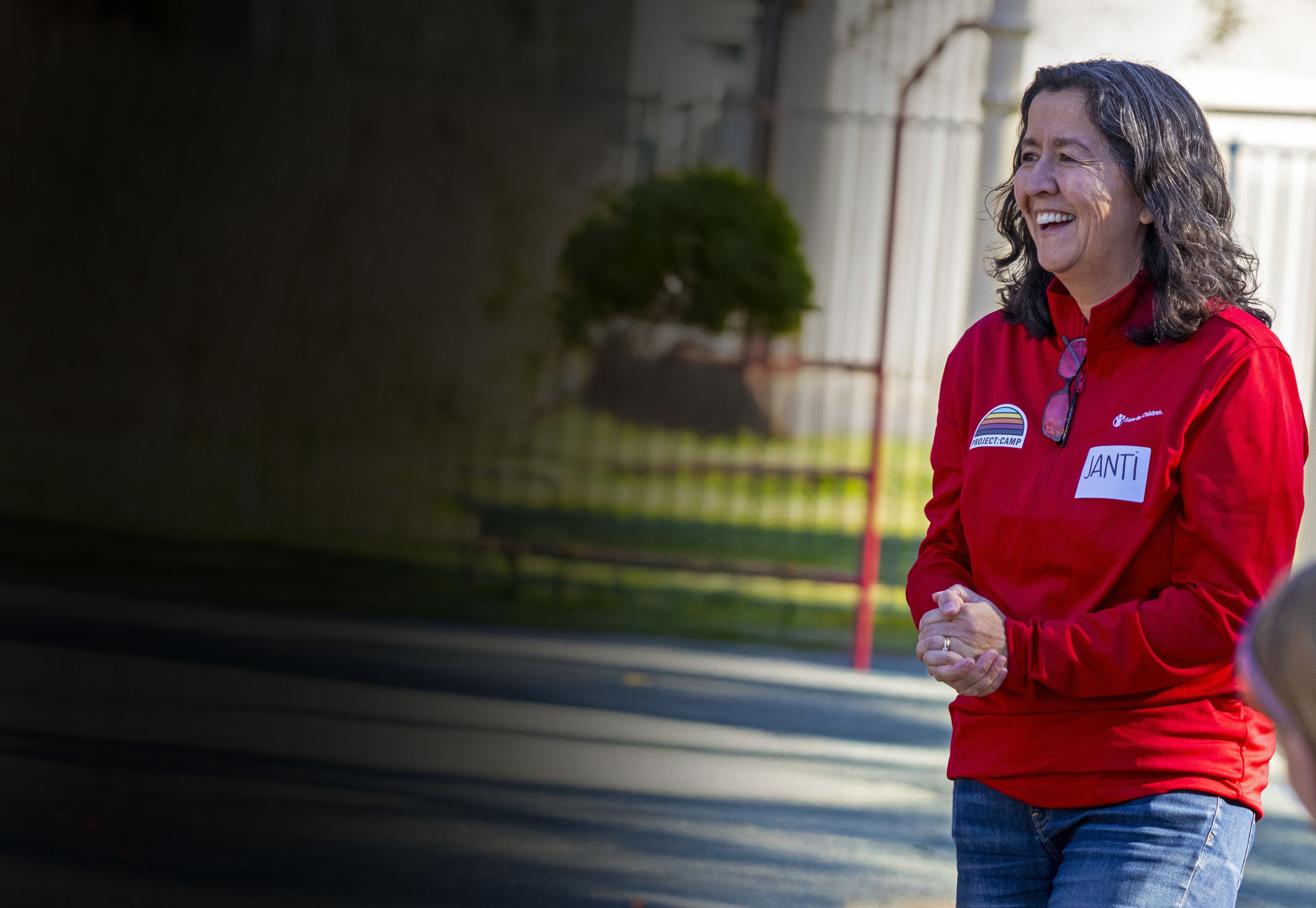 Janti clasping her hands smiling in front of a group of children
