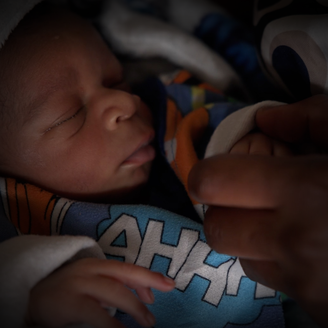 Close up Shekinah* holding her newborn son, Muhindo's hand