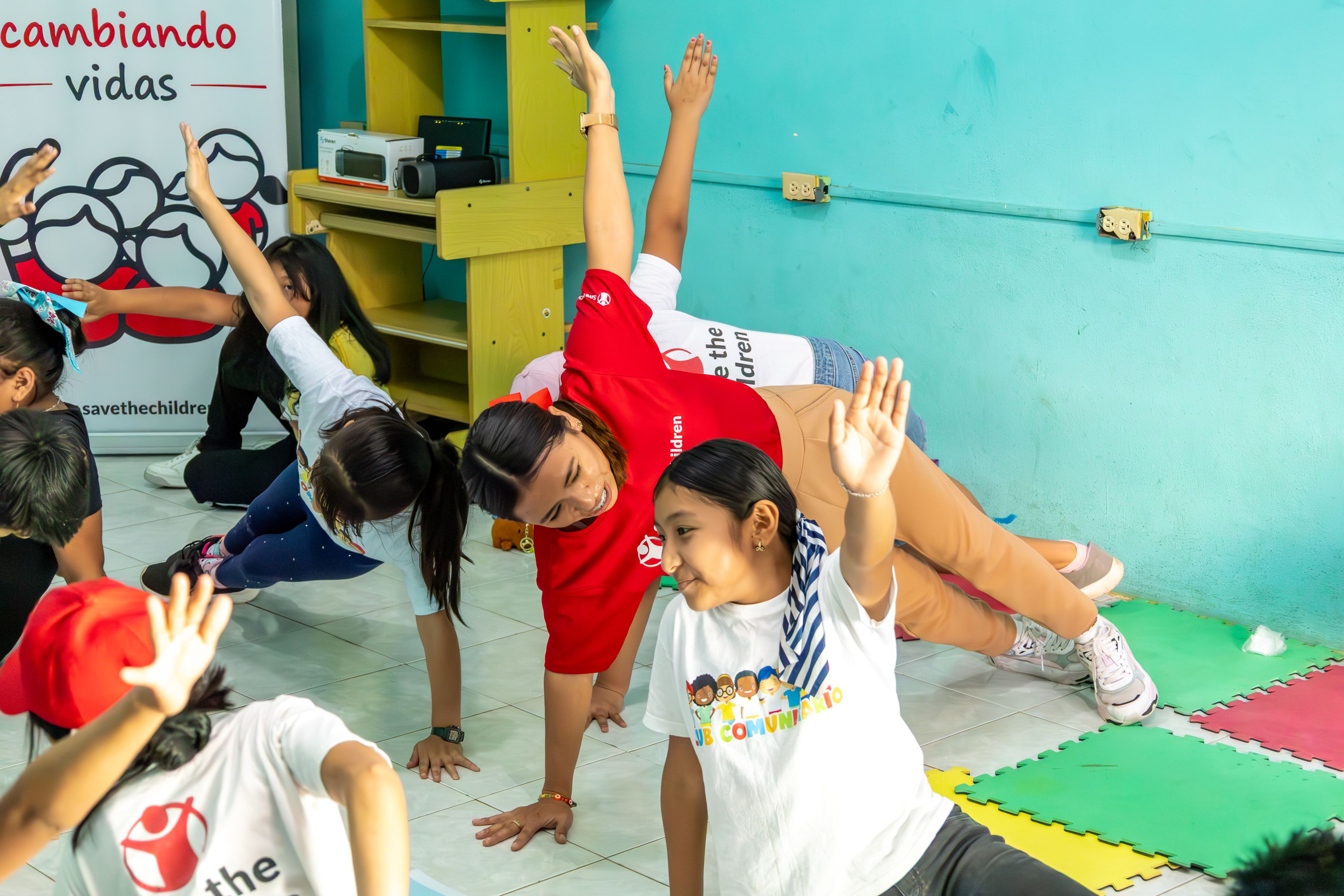 Hilda, a Save the Children promoter, with the children from the community club doing a physical activity
