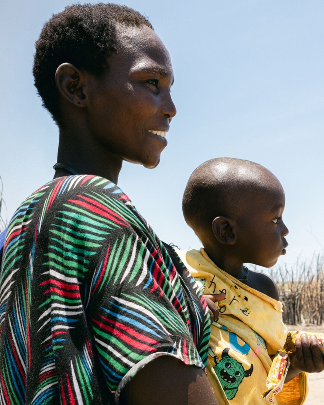 Ng'ikito, 34, holding her 1-year-old son, Dennis, in front of their home
