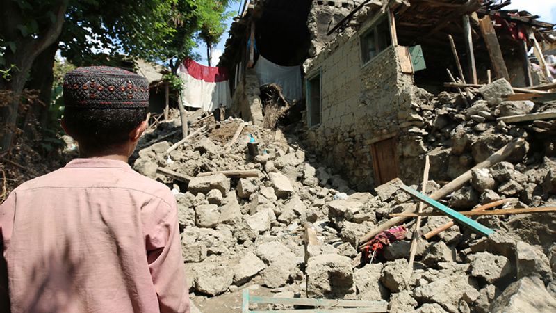 A child looking at rubble from damaged homes