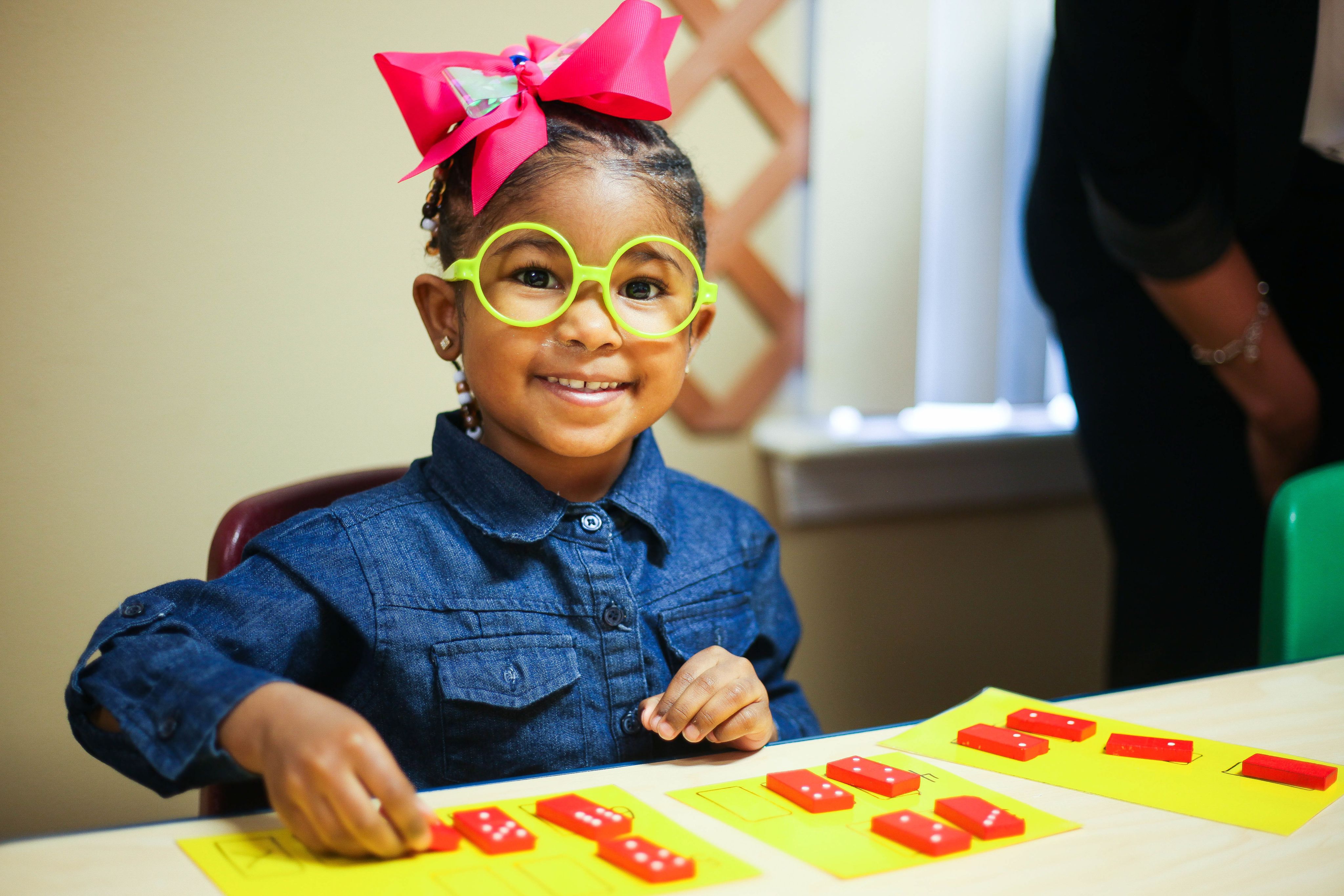 Smiling girl with yellow glasses and large pink hair bow 