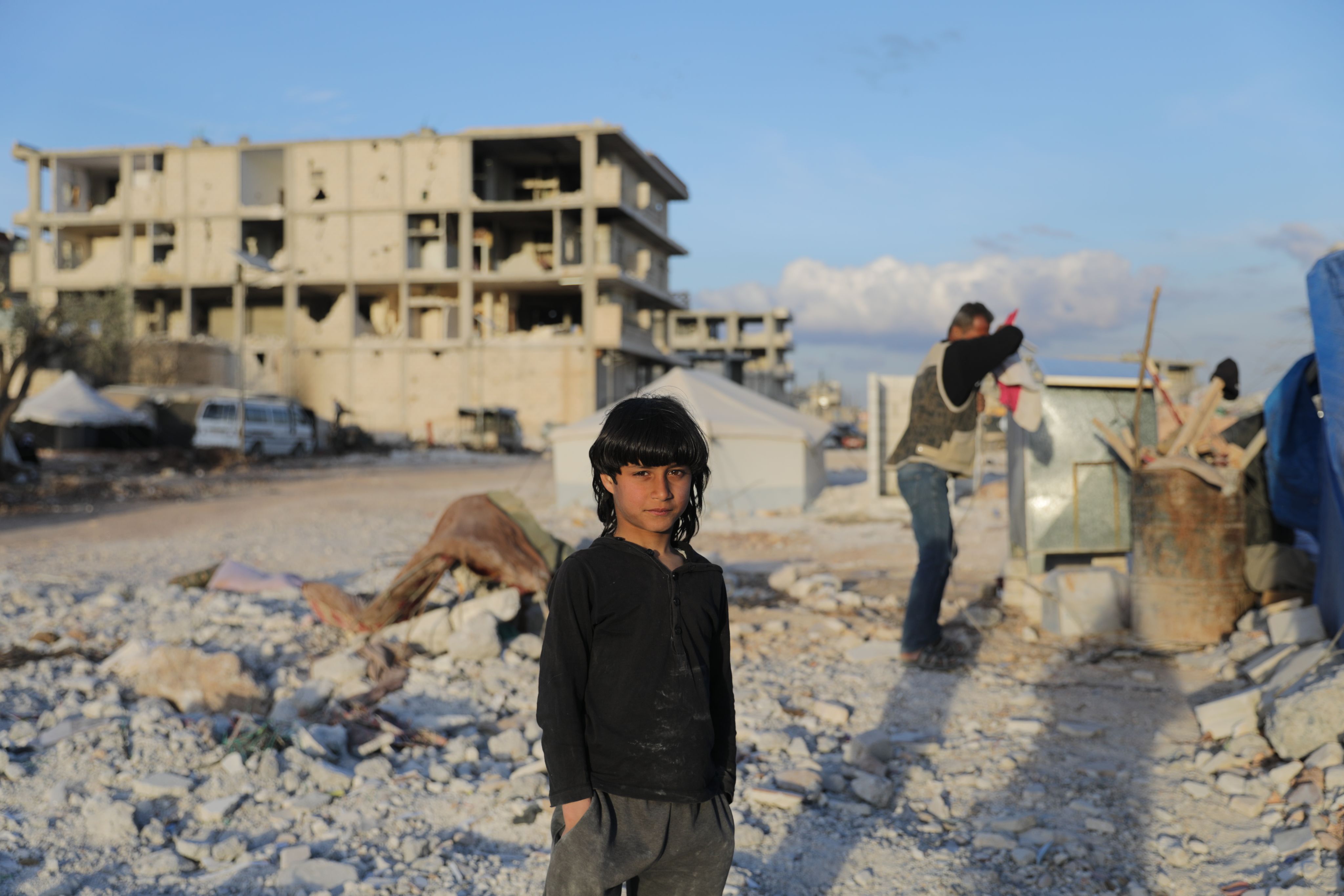 A young child standing in a debris field of what was a building